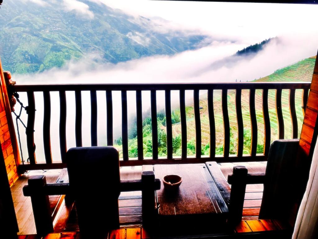 een balkon met een tafel en stoelen bij Baike Boutique Hotel in Longsheng