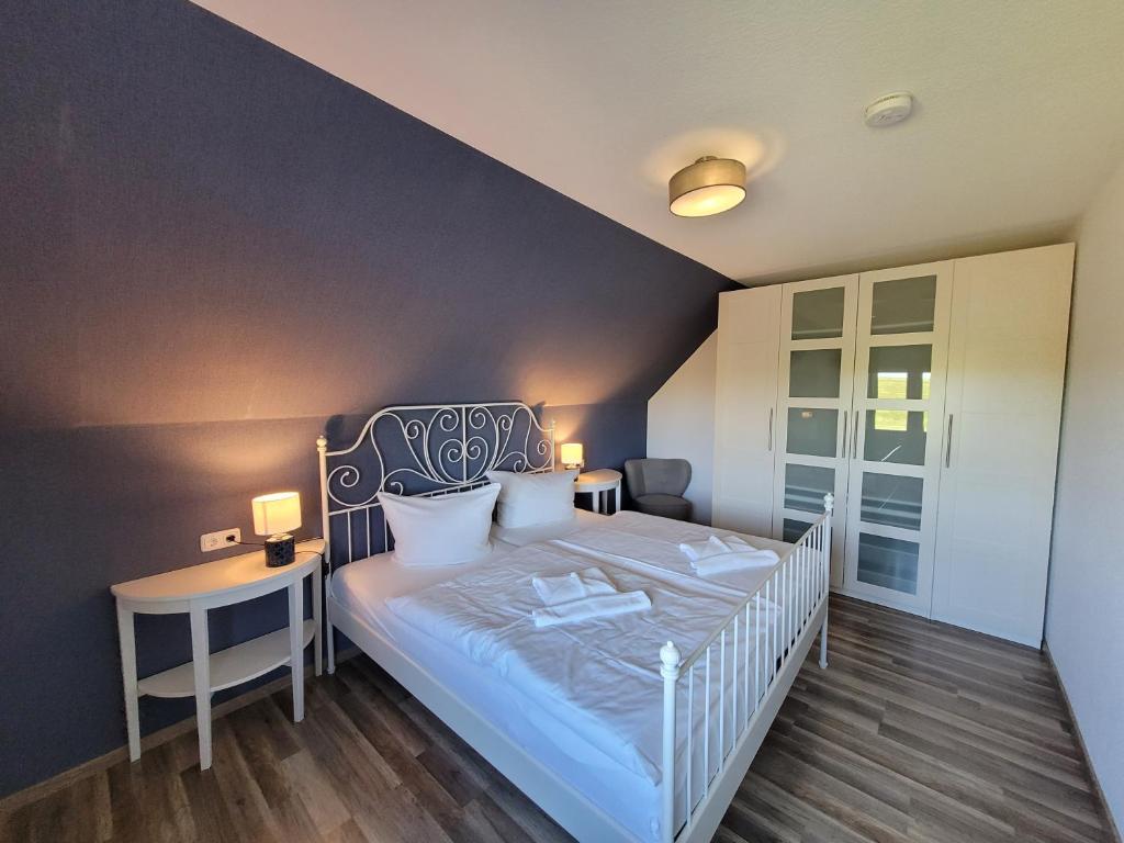 - une chambre avec un lit blanc et une table dans l'établissement Fewo am Yachthafen, à Harlesiel
