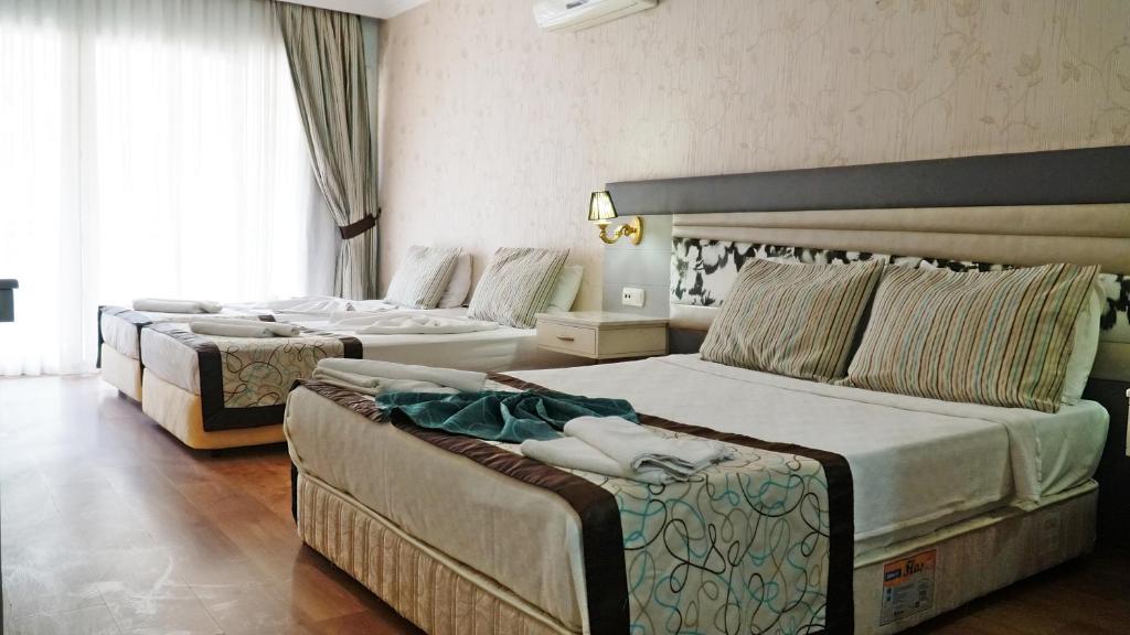 a hotel room with two beds and a large window at RİOS BEACH HOTEL in Beldibi