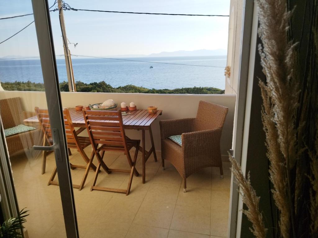 a balcony with a table and chairs and a view of the ocean at Indigo in Rafina