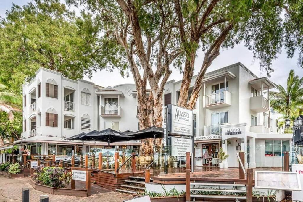 a large white building with a tree in front of it at The Palms Retreat - Alassio Beachfront Resort in Palm Cove