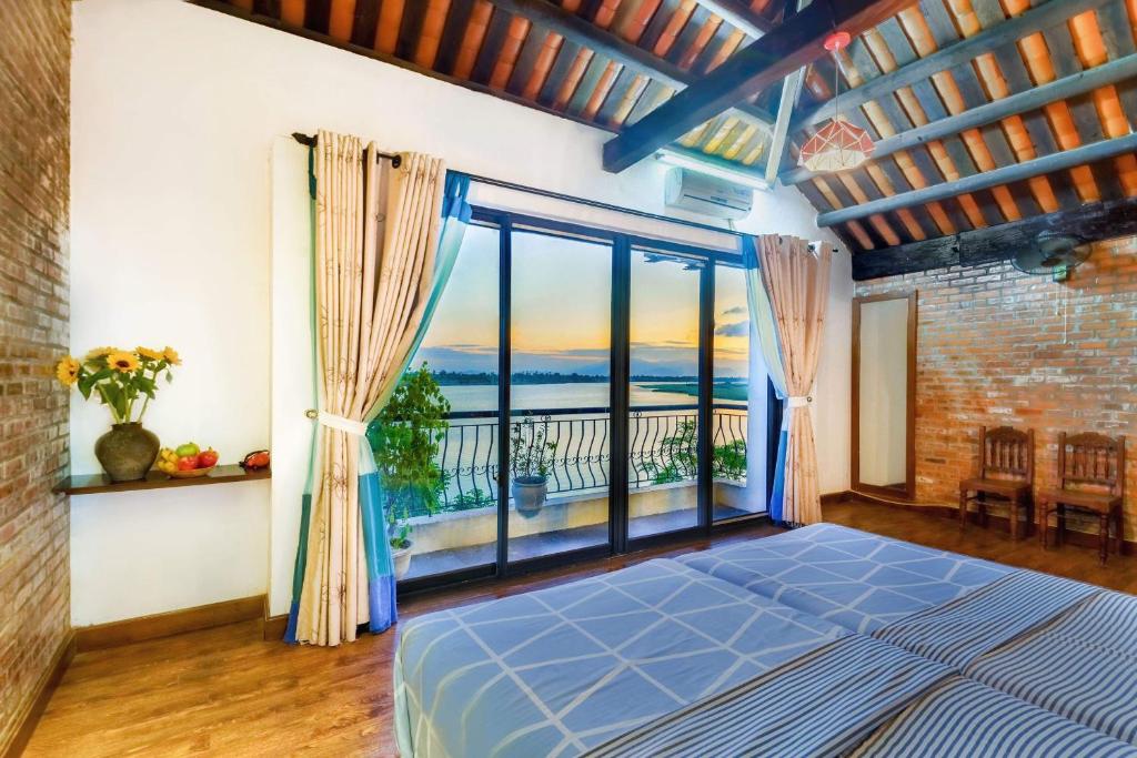 1 dormitorio con cama y ventana grande en Calm House 2 HOSTEL en Hoi An