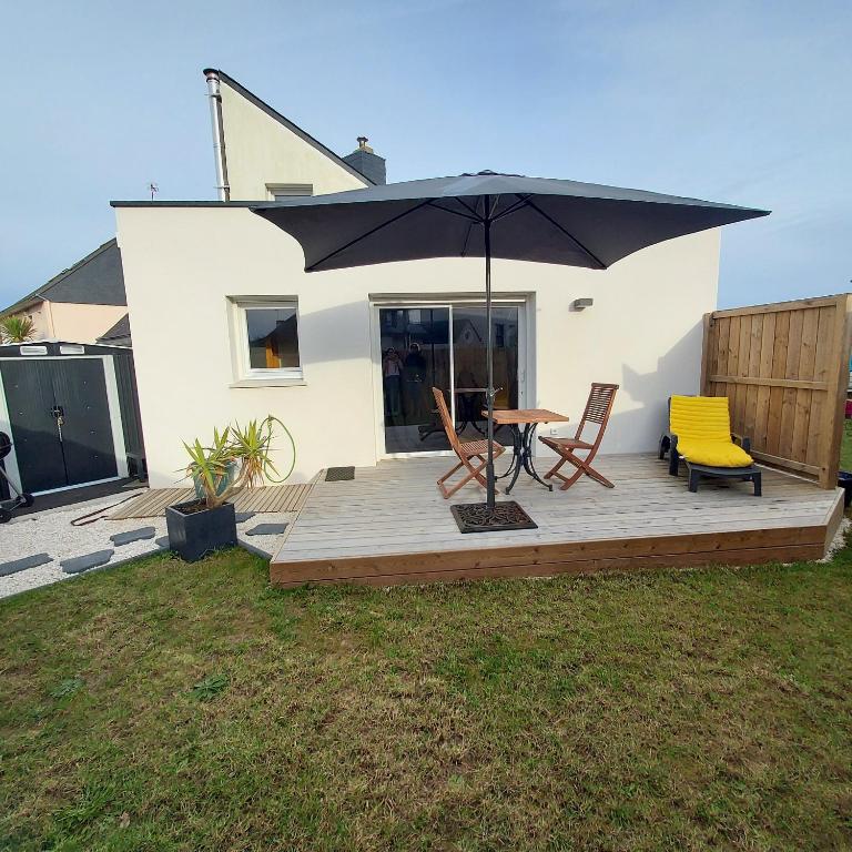 taras z parasolem, 2 krzesłami i stołem w obiekcie Studio avec terrasse et jardin à 100 m de la plage w mieście Ploemeur