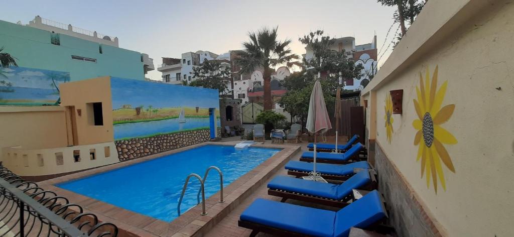 a swimming pool with blue chairs next to a building at Villa Bahri Luxor Apartment in Luxor