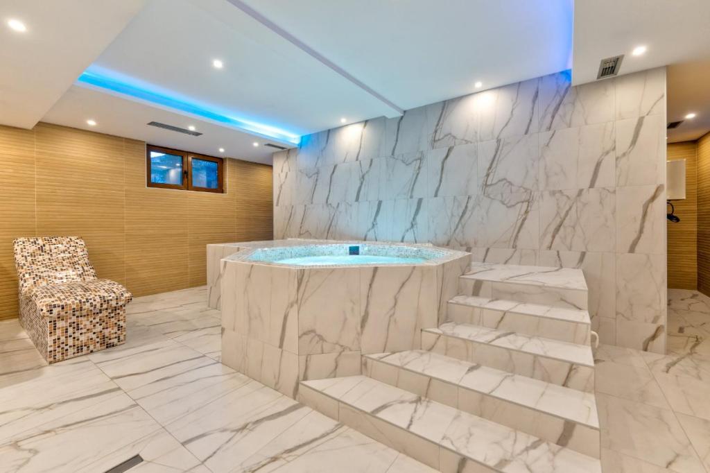 ein Badezimmer mit Badewanne, Stuhl und Treppe in der Unterkunft Vila Zlatibor luxury & spa in Zlatibor