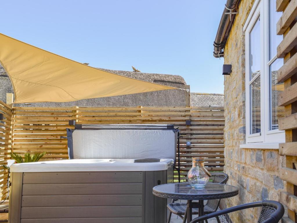 a patio with a hot tub and a table at Dovecote in Stoke Bruerne