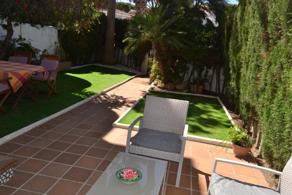 a patio with two chairs and a table and grass at Apartamento en Playa Sancti Petri in Chiclana de la Frontera