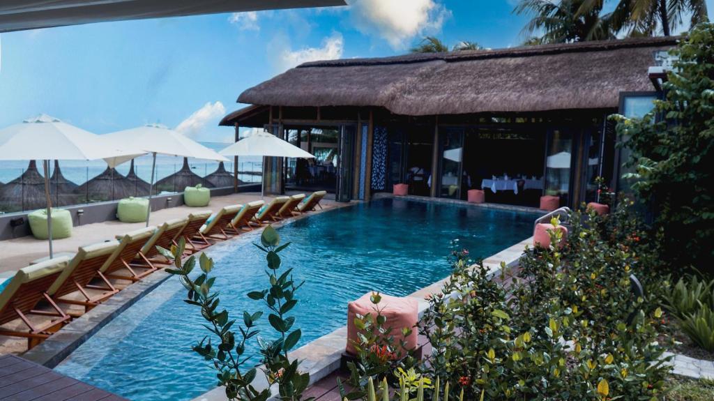 a pool at a resort with chairs and umbrellas at Wonders Beach Boutique Hotel in Mont Choisy