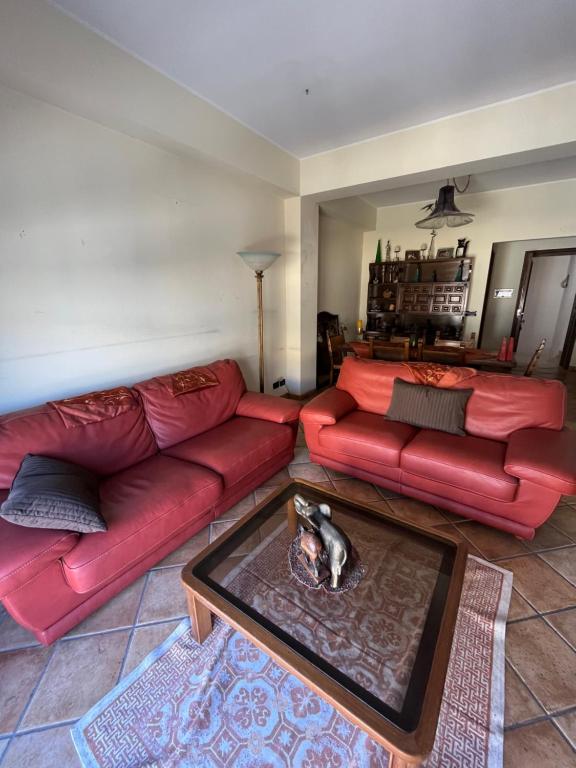 a living room with red couches and a cat laying on a table at La casa nel villaggio dei pescatori in Spadafora