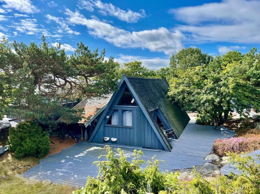 uma pequena casa azul com um telhado inclinado em Fantastic Sea Cottage on Justøya Island, Lillesand em Lillesand