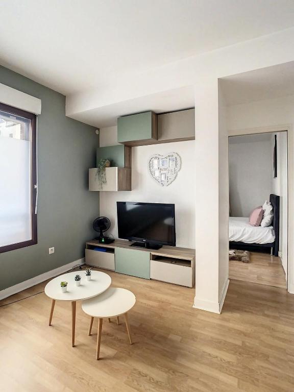 sala de estar con TV, mesa y cama en Grand Appartement Paris et Disneyland 4pers, en Neuilly-sur-Marne