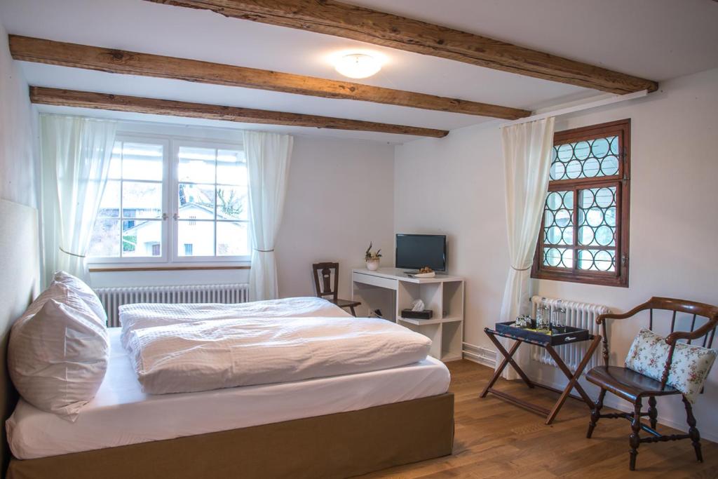 a bedroom with a bed and a desk and a window at 3 Sterne Boutique Gasthaus Pöstli in Rifferswil