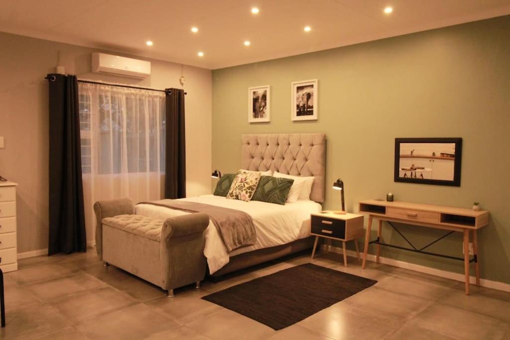 a bedroom with a bed and a chair and a table at Clifton Home in Richards Bay