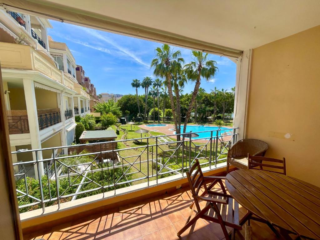 d'un balcon avec vue sur la piscine et les palmiers. dans l'établissement Playa San Juan Golf, à Alicante