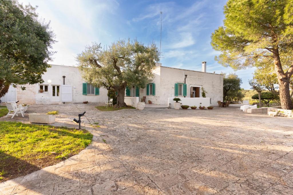 ein großes weißes Gebäude mit grünen Rollläden in der Unterkunft ITRIUM Homes & Suites in Valle d'Itria in Alberobello