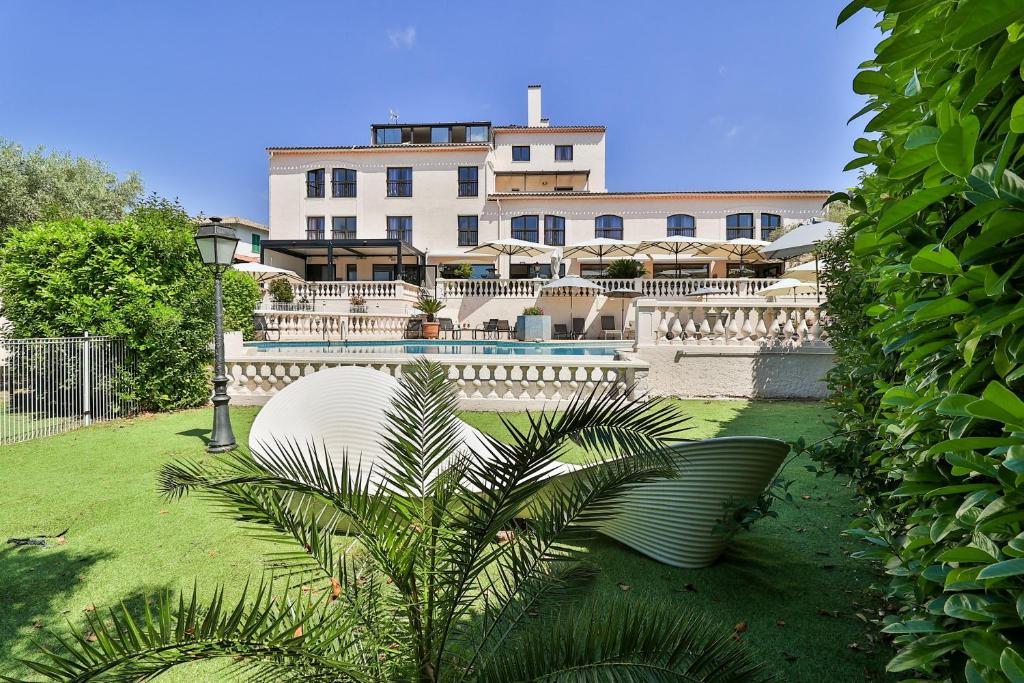 a building with a palm tree in front of a building at Hotel & Restaurant Perla Riviera in Villeneuve-Loubet