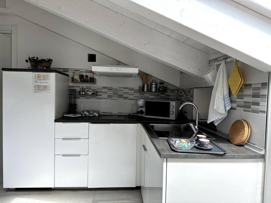 a small kitchen with white cabinets and a sink at The sweet attic room - De Vivo Realty Meta di Sorrento in Meta