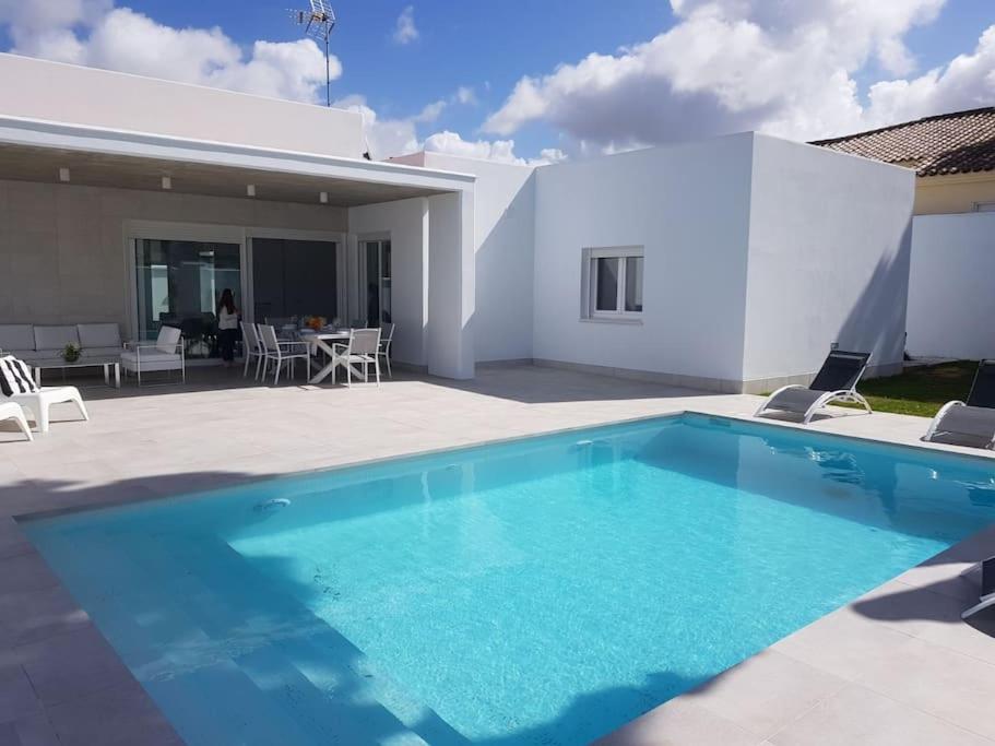 una gran piscina azul frente a una casa en CHALET ARRILUCE Plaza de parking gratis en la playa SOLO FAMILIAS en Chiclana de la Frontera