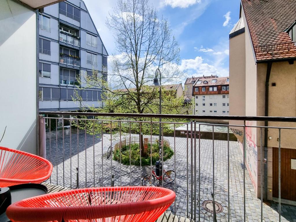 a balcony with red chairs and a view of a courtyard at LINDE3 - 10 Minuten in die Altstadt mit Balkon und Pegnitzblick in Nürnberg