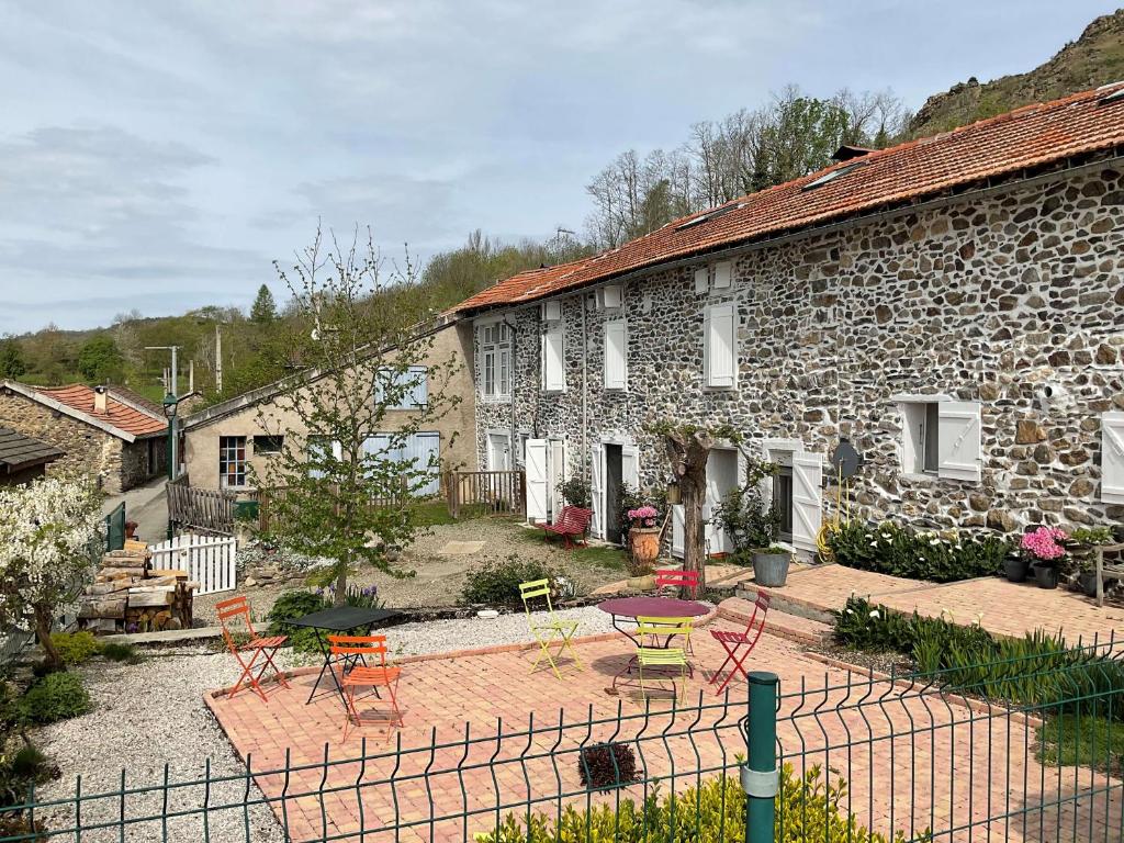 a stone house with a yard with chairs and tables at La Bruyère - chez Martine in Appy