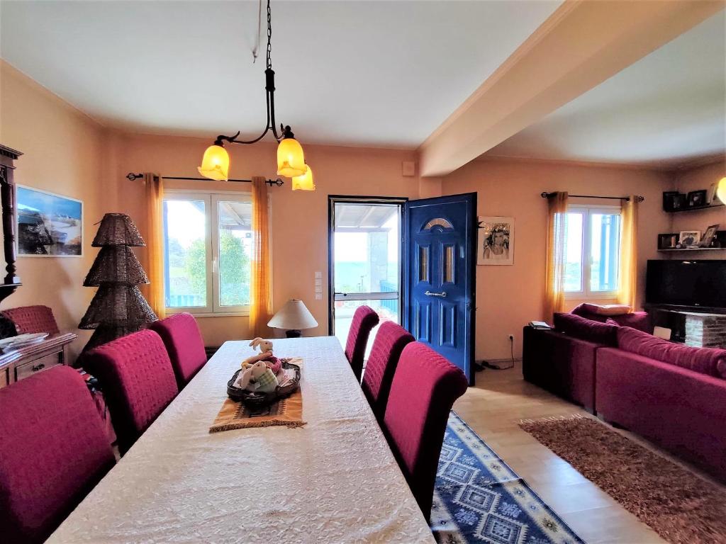 a dining room with a long table and pink chairs at Batsi Bay View Maisonette in Andros