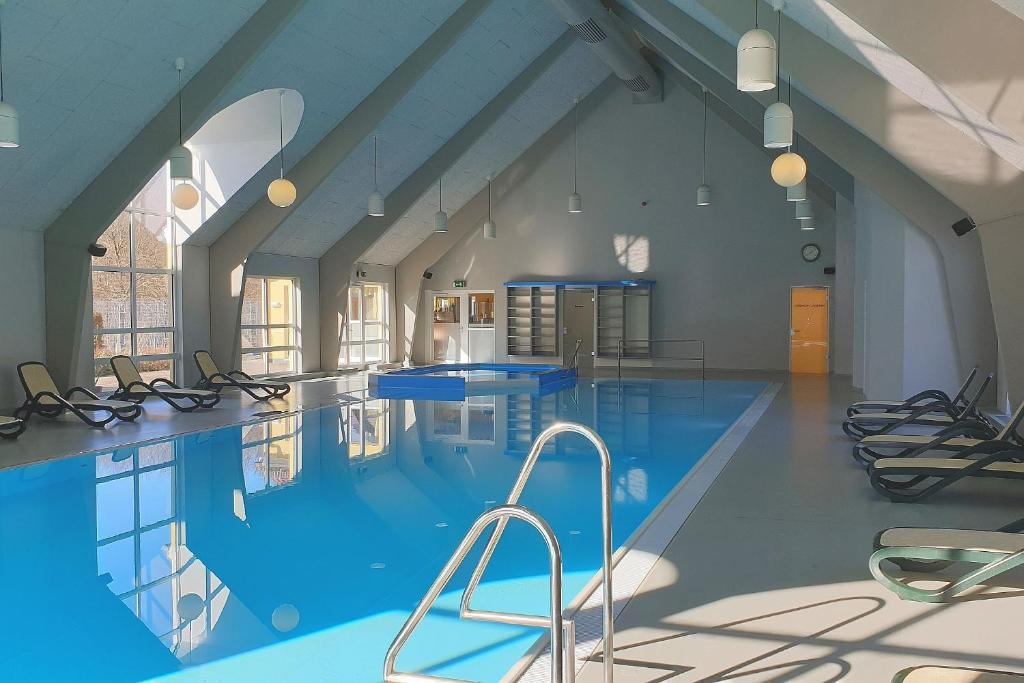 a large swimming pool with blue water in a building at Vineta Ferienpark Usedom in Ostseebad Koserow