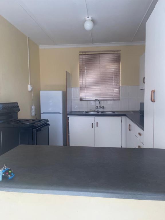 een keuken met witte kasten en een witte koelkast bij Mercy Land Guesthouse in Matatiele