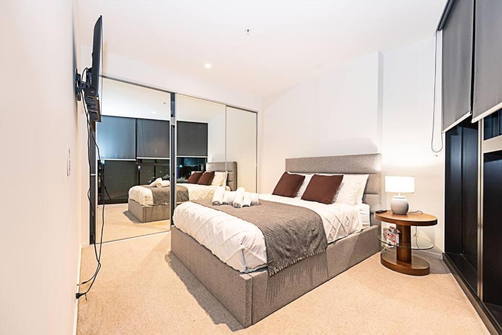 Un dormitorio con una cama grande y un espejo grande. en Bright Urban Oasis, en Melbourne