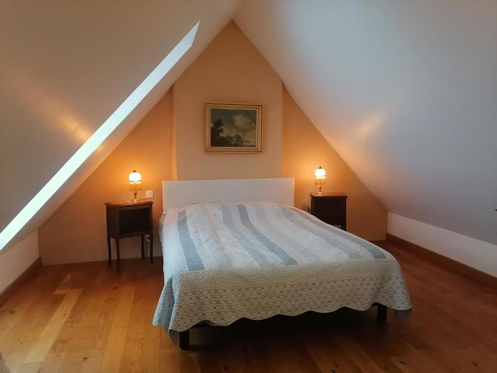 a attic bedroom with a bed and two night stands at Frairie Du Divit in Pontivy