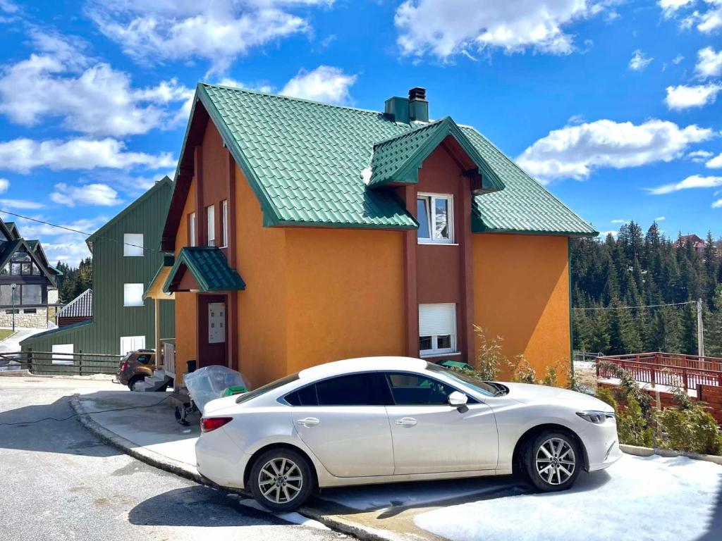 a white car parked in front of a house at Family Two-bedroom apartment Zabljak in Žabljak
