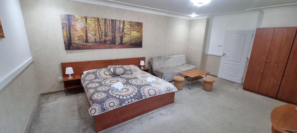 a bedroom with a bed and a chair and a painting at Apartman Afrodita 1 in Bardejovské Kúpele