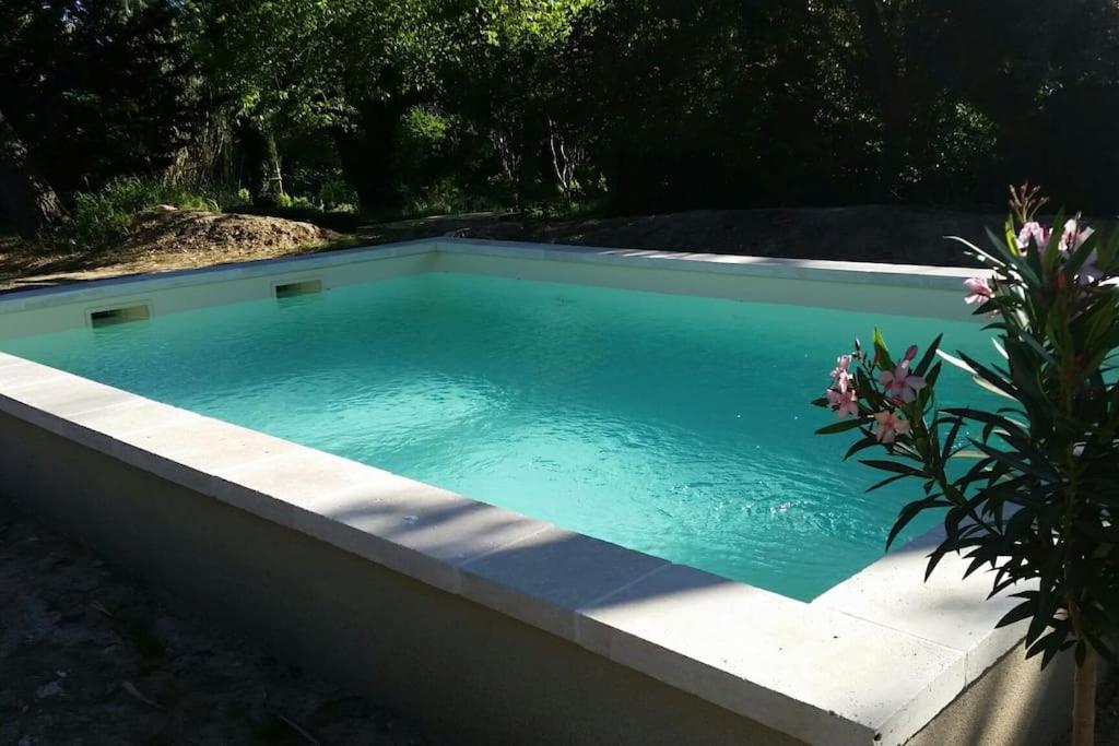 a swimming pool with blue water in a backyard at Le Pigeonnier in Vaison-la-Romaine