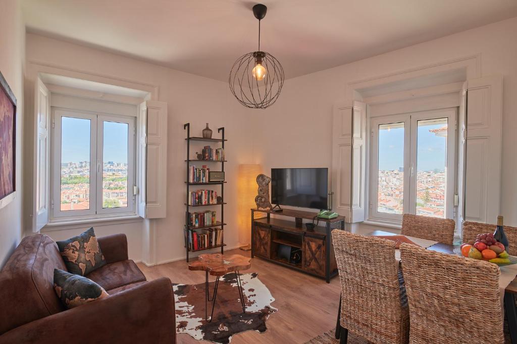 uma sala de estar com um sofá e uma televisão e janelas em The Blue Sky Nest em Lisboa