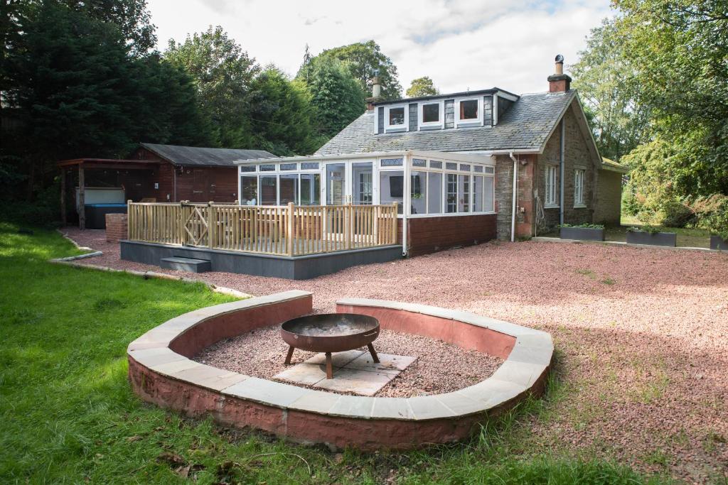 a backyard with a fire pit in front of a house at Auchendennan Farm Self Catering Cottages in Balloch