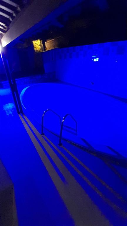 a swimming pool with blue lights in a dark room at Pelados Beach Hostel in Pipa