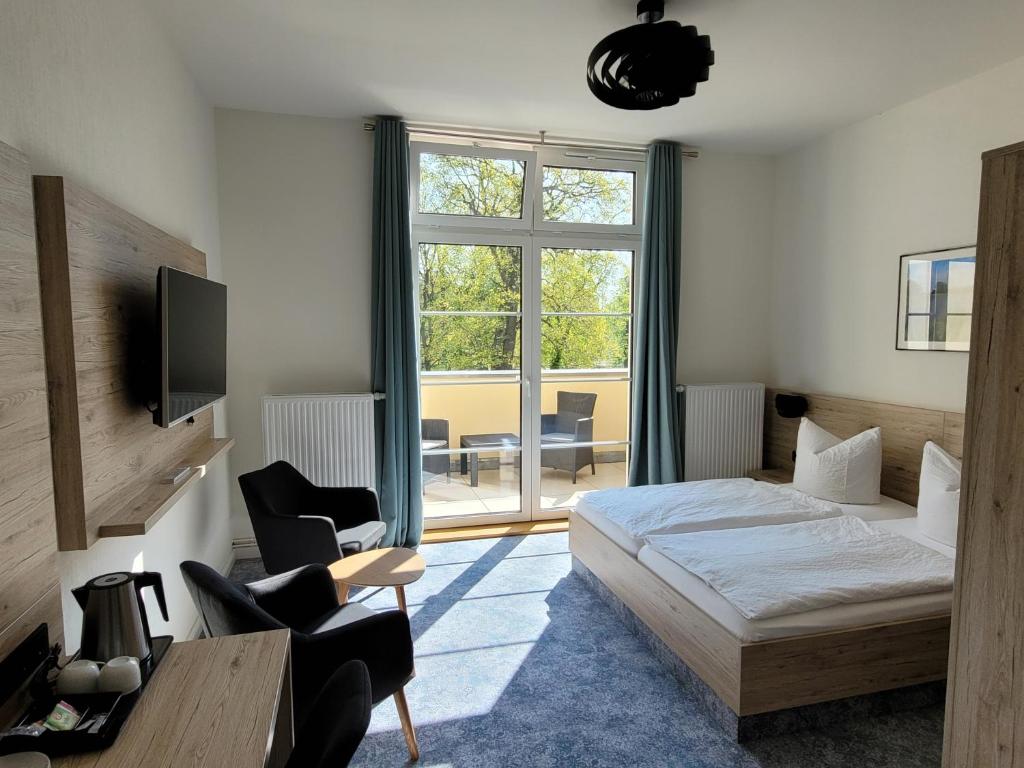 a bedroom with a bed and a chair and a window at Pension zum Kleistpark in Frankfurt Oder
