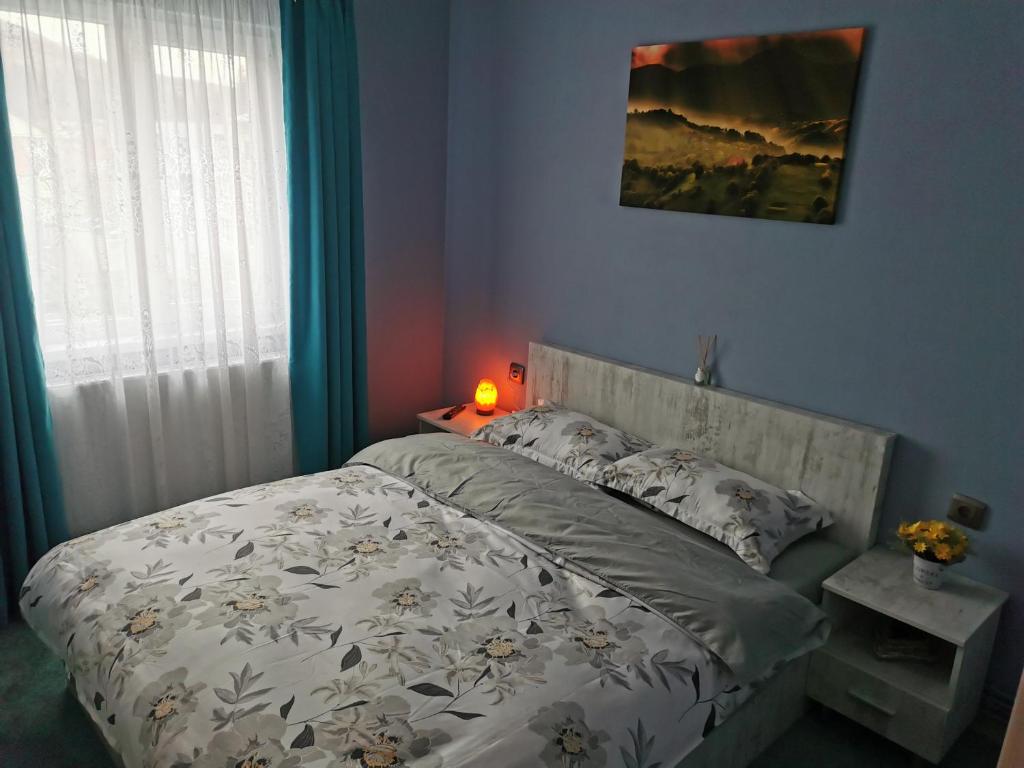 a bedroom with a bed with a white comforter at Apartament Ramona in Zărneşti