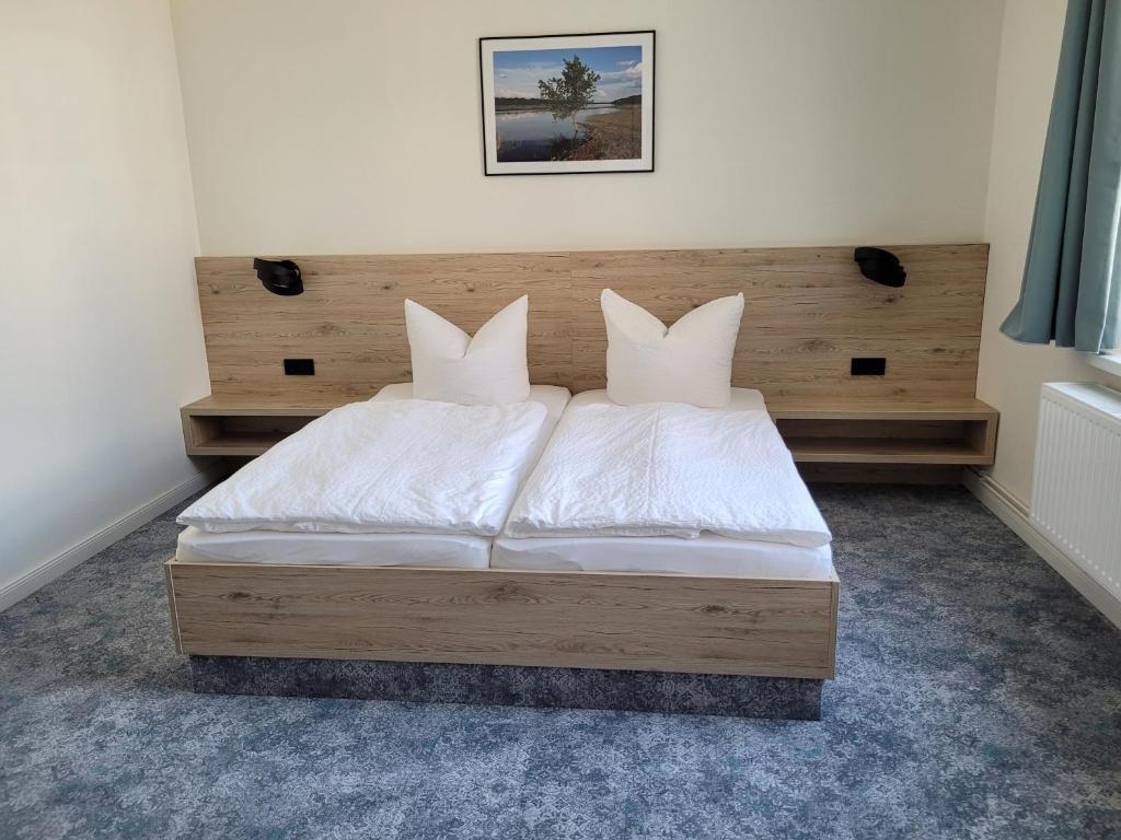 a bed with white sheets and a wooden headboard at Pension zum Kleistpark in Frankfurt Oder