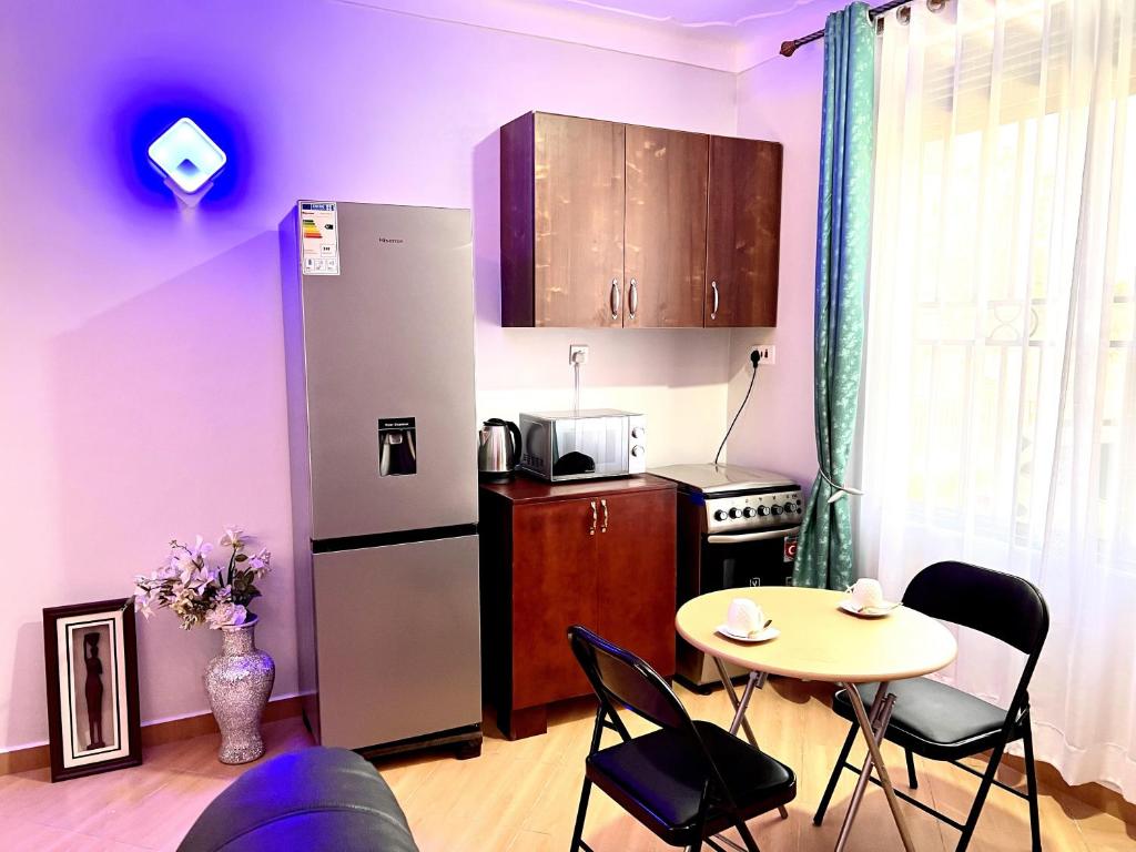 a small kitchen with a table and a refrigerator at Elvina Home Buziga in Kampala