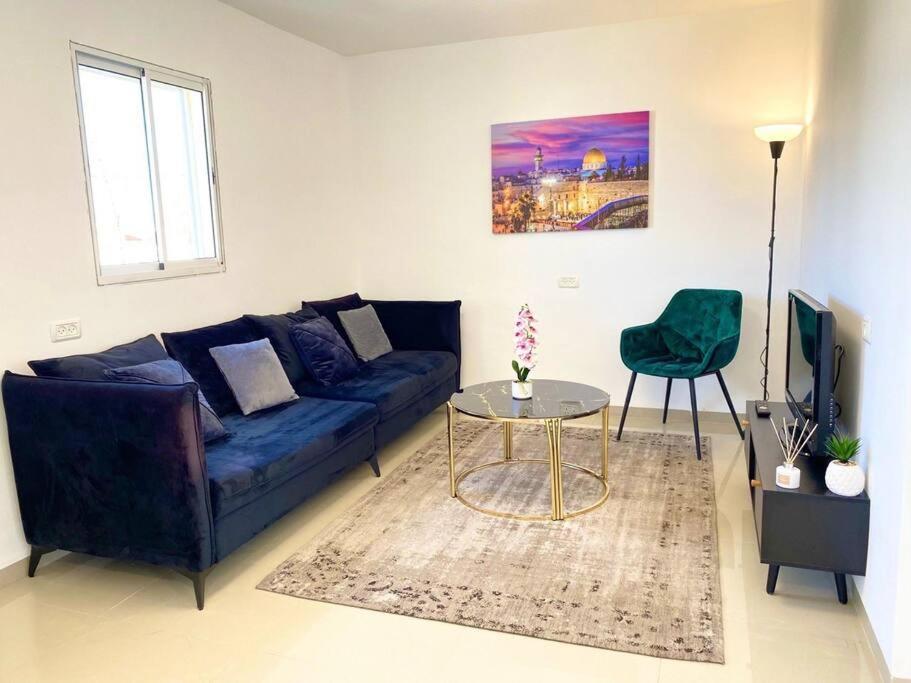 a living room with a blue couch and a table at Chic apartments next to the sea in Qiryat Yam
