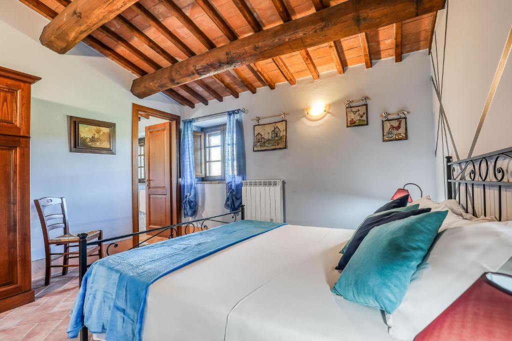 ラディコーファニにあるAgriturismo Podere San Giorgioの白いベッドと木製の天井が備わるベッドルーム1室が備わります。