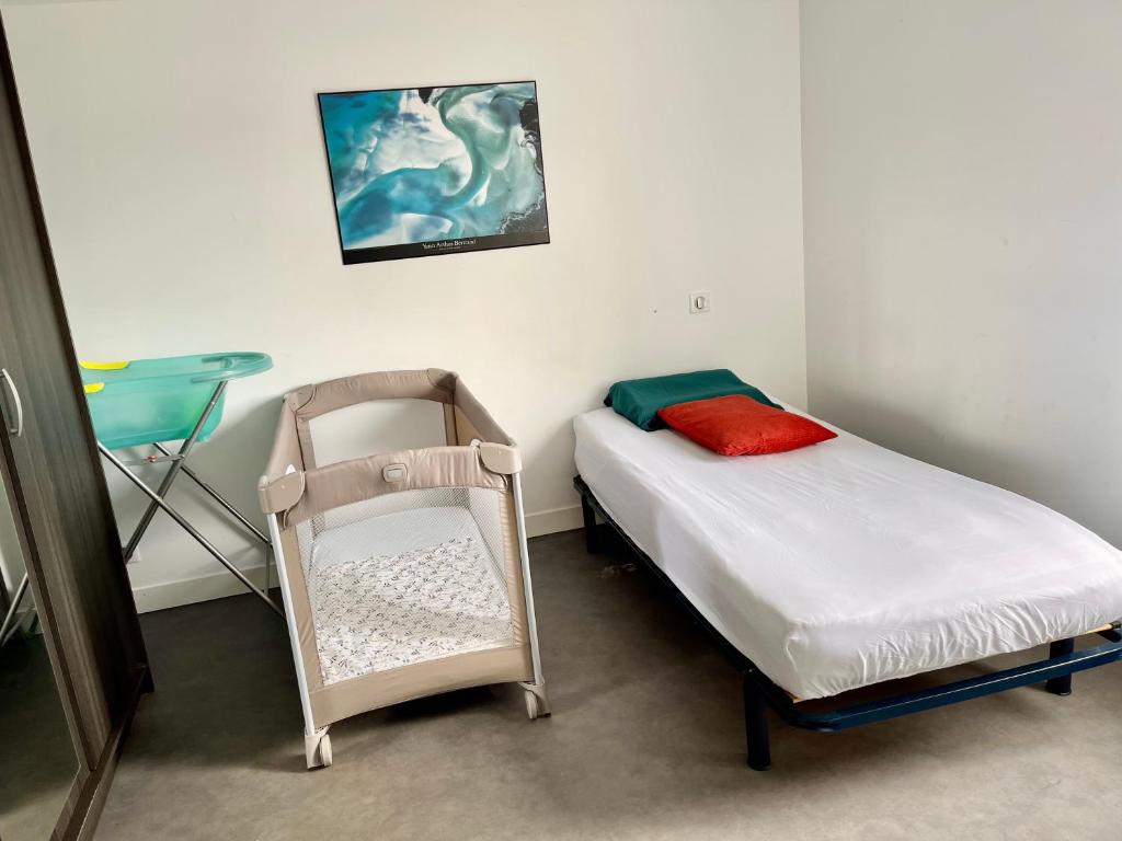 ein kleines Schlafzimmer mit einem kleinen Bett und einem Stuhl in der Unterkunft La villa des retrouvailles in Ploufragan