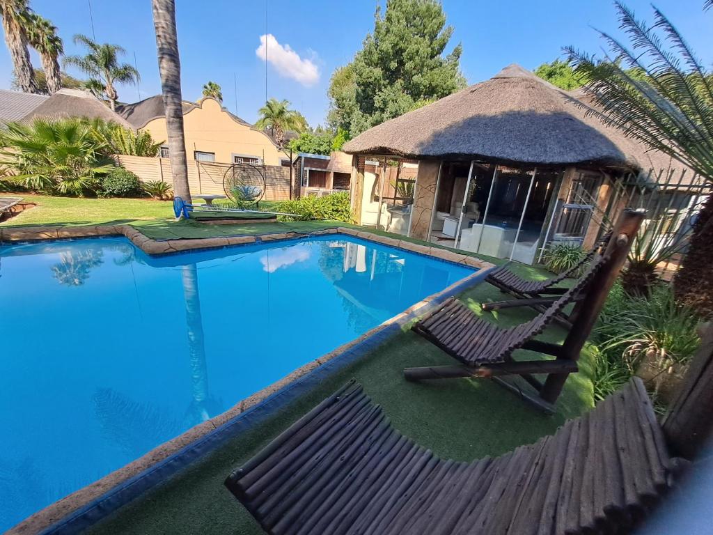 a swimming pool with two chairs next to a house at Residential Inn in Pretoria