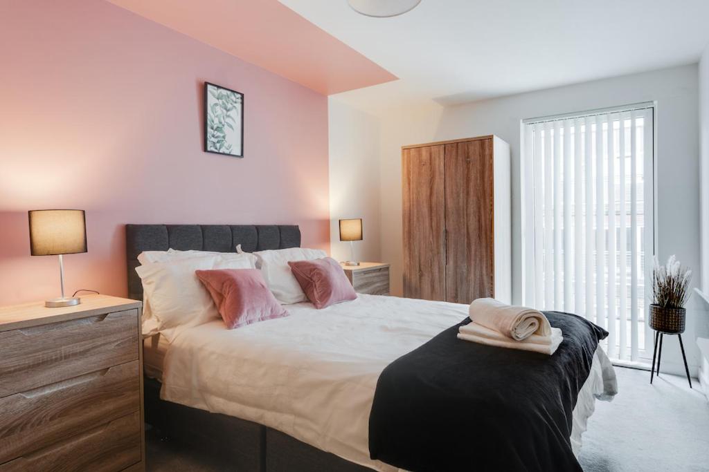 1 dormitorio con 1 cama grande y paredes de color rosa en City Living Penthouse Apartment with Parking (Manchester) en Mánchester