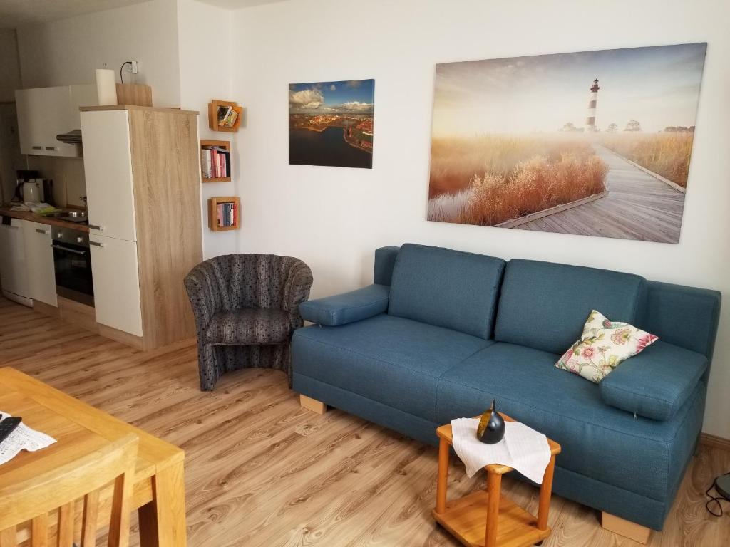 ein Wohnzimmer mit einem blauen Sofa und einem Tisch in der Unterkunft Altstadt Ferienwohnung Stralsund mit Parkplatz in Stralsund