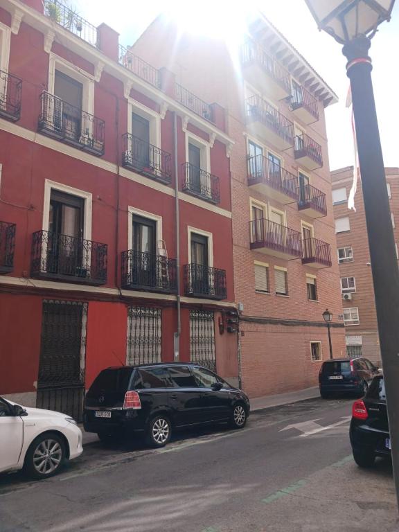 dos coches estacionados frente a un edificio en Habitación en Madrid, en Madrid