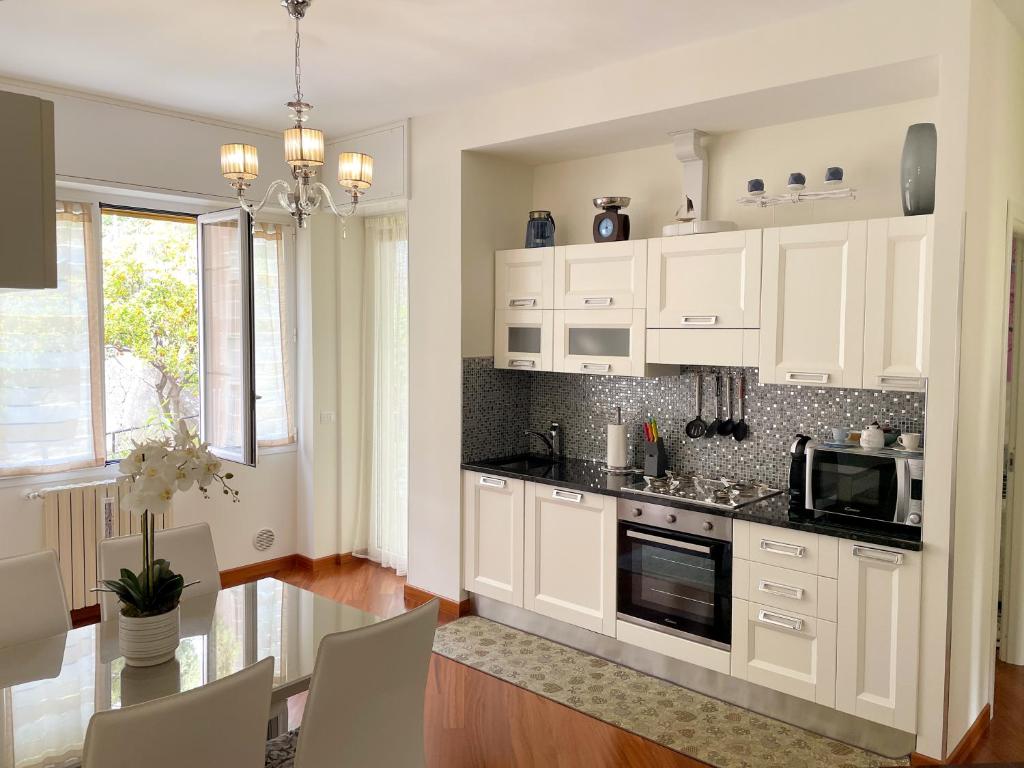 a kitchen with white cabinets and a table with chairs at Casa Corallo Vicino alle Spiagge in Sanremo