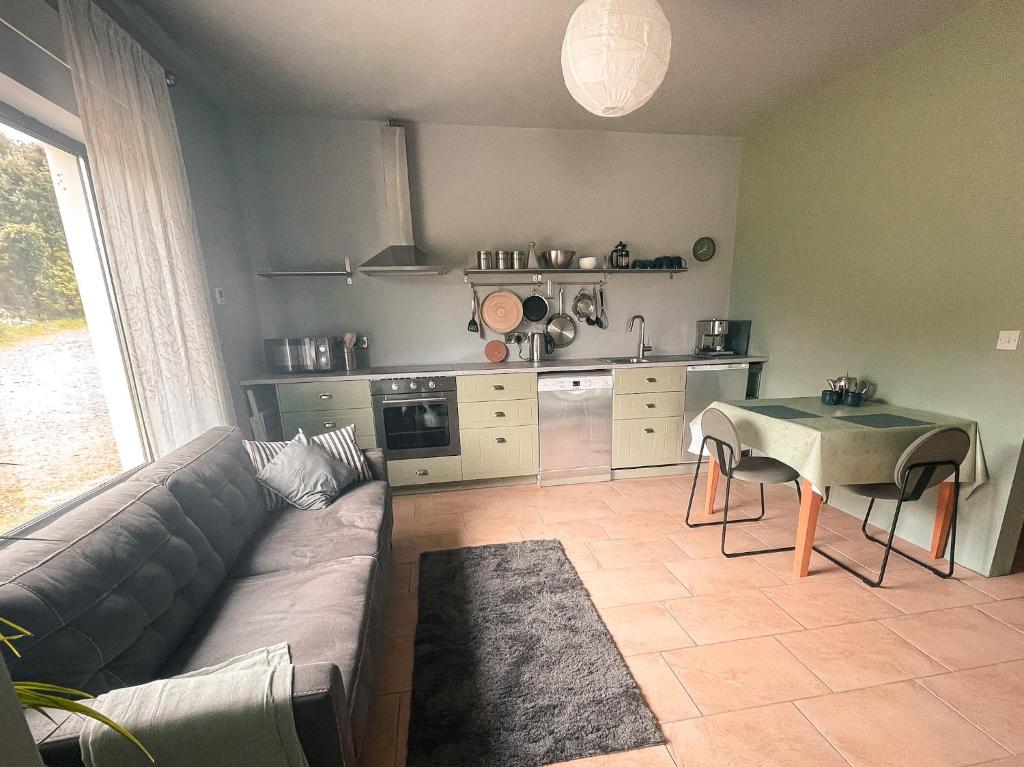a living room with a couch and a table and a kitchen at The Blue Door Apartment in Cahersiveen