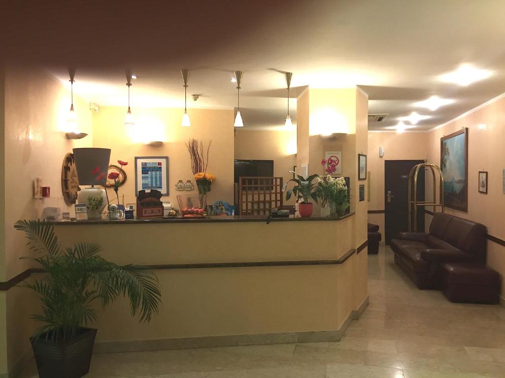 a lobby with a reception counter and a couch at Hôtel Vesuvio in Lourdes
