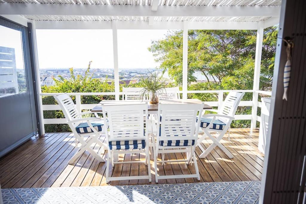 una mesa de comedor blanca y sillas en un porche en AirTulla, en Port Elizabeth
